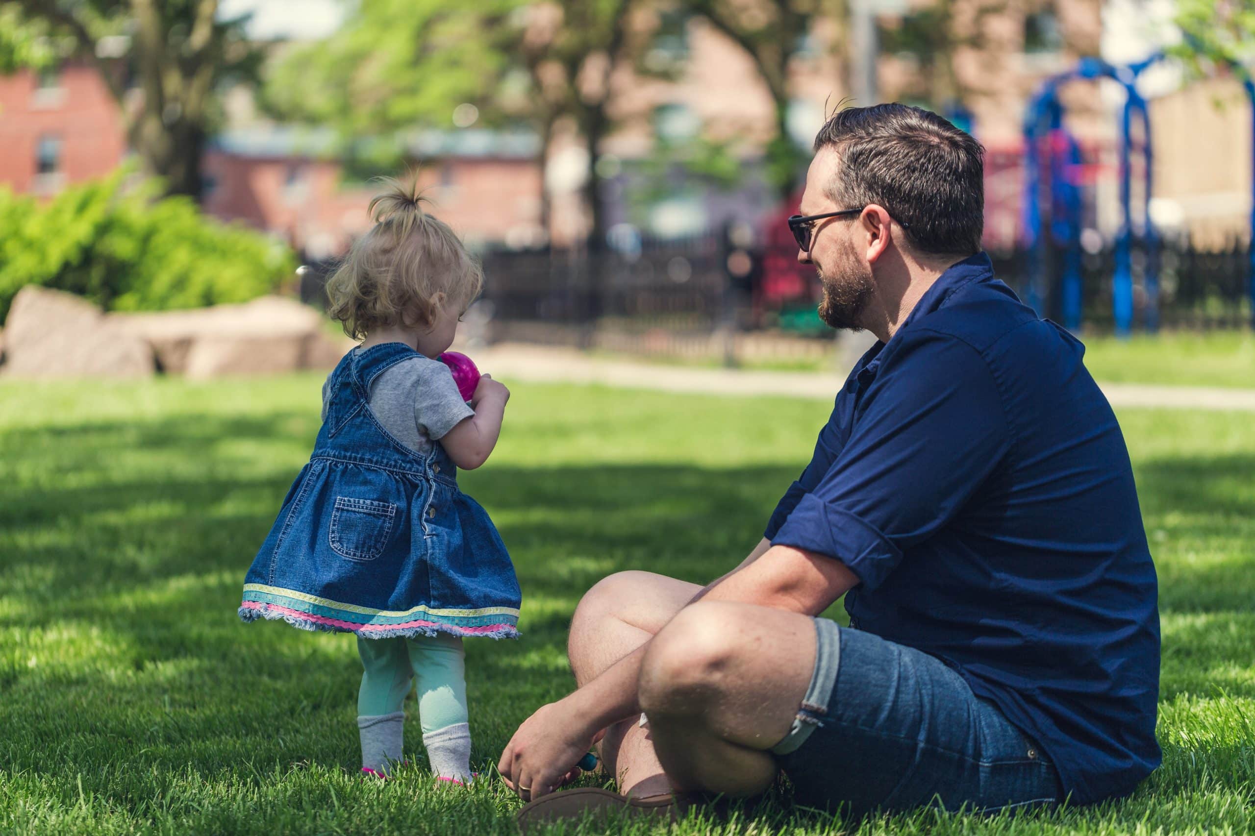 dad-at-the-park A father sitting on the grass at the park with a toddler girl