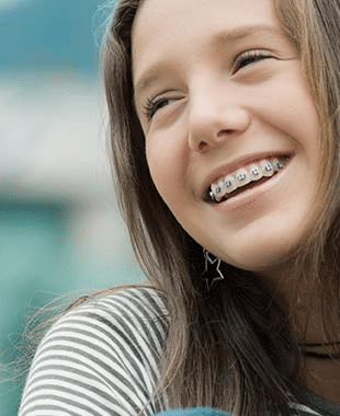 A smiling teenage girl with braces, outdoors